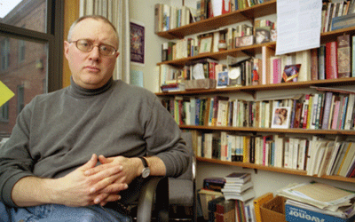 Doug Green sitting in office, bookshelf with many books behind him.